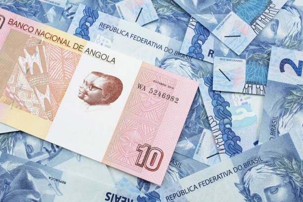 An Angolan ten kwanza bill with Brazilian two reais bank notes An red and white ten Angolan kwanza bank note on a background of Brazilian two reais bank notes angolan kwanza photos stock pictures, royalty-free photos & images