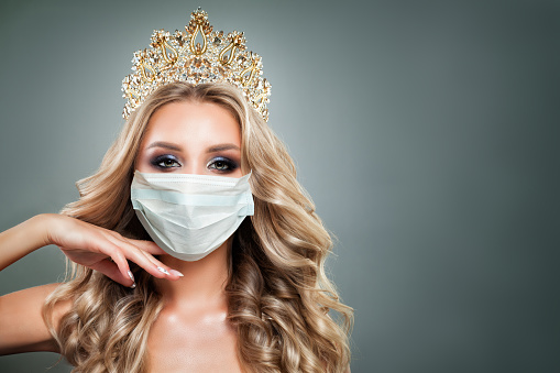 Beautiful fashion model woman in medical face mask and diamond crown