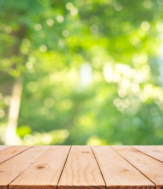 istock Real wood table top texture on blur leaf tree garden background.For create product display or design key visual 1221652882