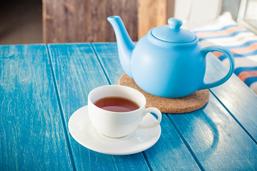 Cup of tea with the blue teapot on the table
