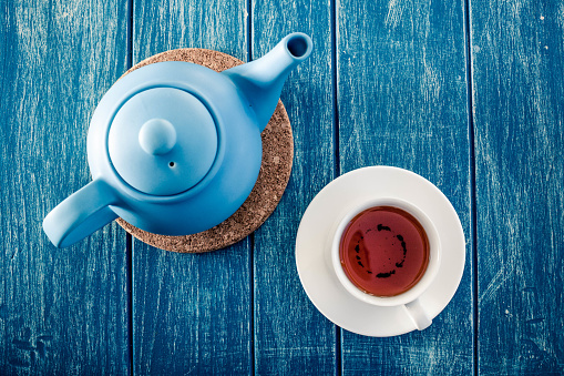 Cup of tea with the blue teapot on the table