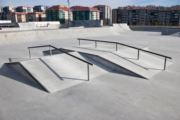 istock Sloped metal rails for grind tricks in an empty concrete skatepark 1221661740