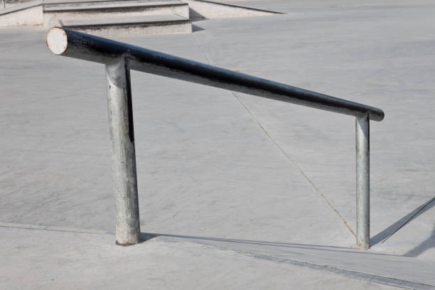 istock Sloped metal rail for grind tricks in an empty concrete skatepark 1221661840