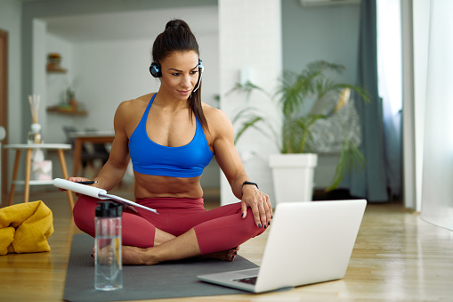 Female fitness instructor having online consultations while using computer in the living room.