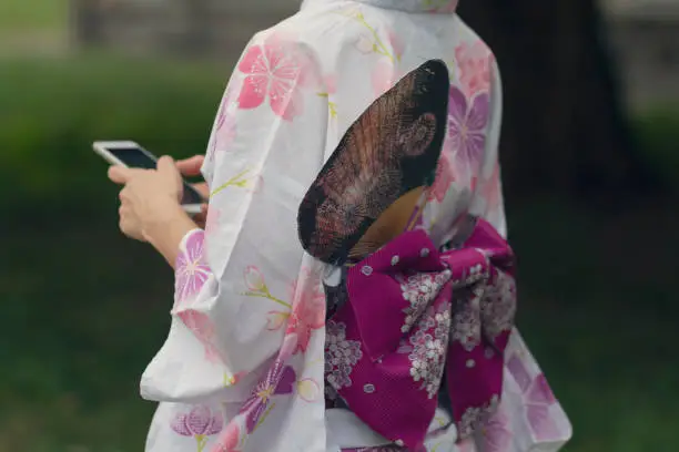 Girl in a beautiful kimono with a smartphone. Japanese culture