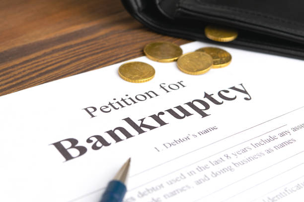 istock Close-up bancruptcy petition, pen and golden coins from wallet. 1221666207