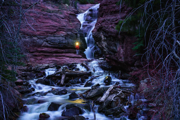 Man Hiking Waterfall in Nature at Dusk - Getting dark in canyon using headlamp to navigate during twilight.