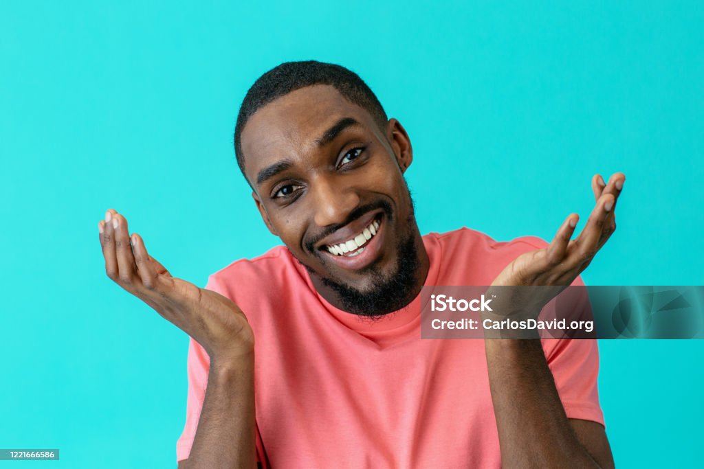 Portrait of a young man smiling and gesturing with hands out, isolated on blue studio background Lifestyles Stock Photo