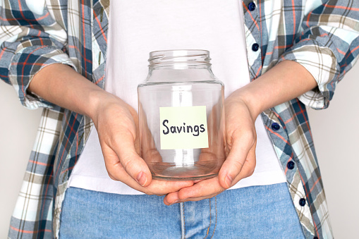 Young woman in casual clothes hold empty glass jar for savings. Bankruptcy concept.
