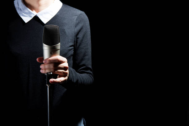 istock Female singer on the stage holding a microphone on a dark background 1221670643