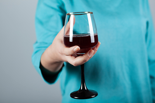 woman hand glass of wine on grey wall background