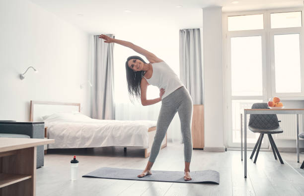 istock Happy brunette girl doing stretching exercises at home 1221674996