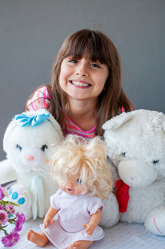 Little cute girl happiness at balcony with her teddy bear, doll and plush rabbit