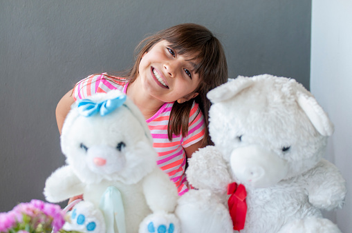 Little cute girl happiness at balcony with her teddy bear and plush rabbit