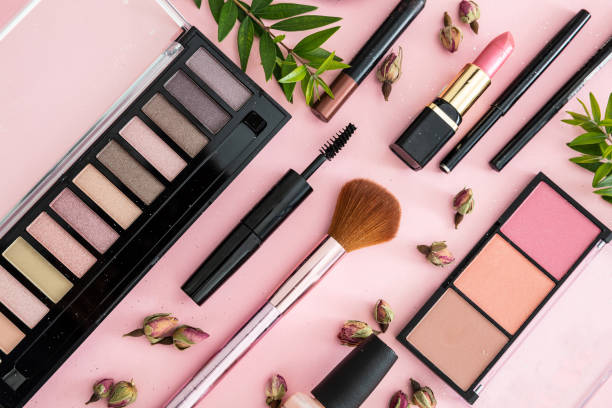 Make up cosmetics products against pink color background Make up natural cosmetics flat lay. Lipstick and nail polish, eye shadows and blush, brushes, pencils and rose buds against pink color background. beauty product stock pictures, royalty-free photos & images