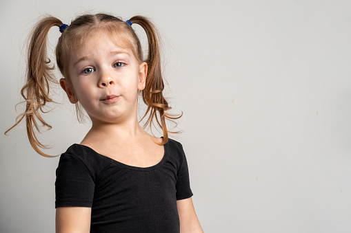 portrait of a 3-4 year old emotional girl with two ponytails in a black t-shirt