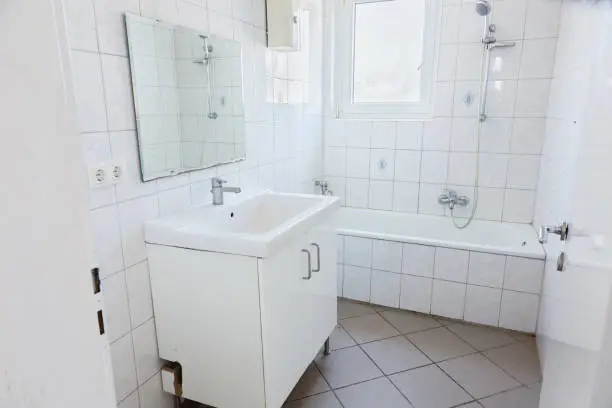 simple bathroom with sink, mirror and bathtub in a small room with white tiles at the wall