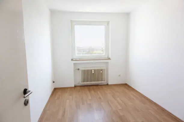 Small room with white walls and wooden flooring, could be used as a bedroom for a child