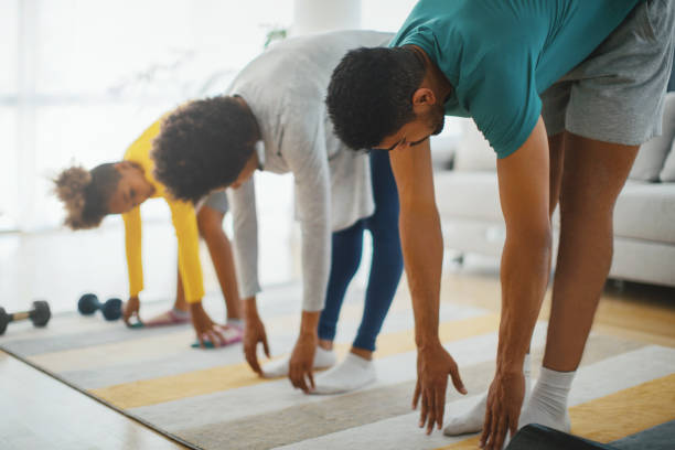 Family exercising at home. Family is exercising at the time of the coronation virus quarantine. They try to stay healthy. touching toes stock pictures, royalty-free photos & images