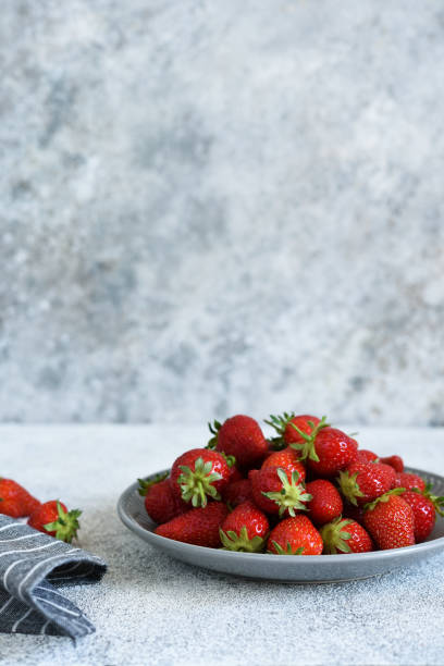 istock Fresh strawberries in a plate on a concrete background with place for text. Horizontal focus. 1221680099