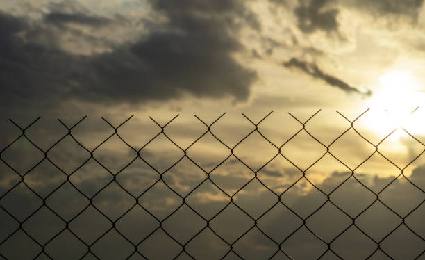 istock Restricted area concept. A metal mesh fence enclosing a restricted area (quarantine, prison, production area) 1221680782