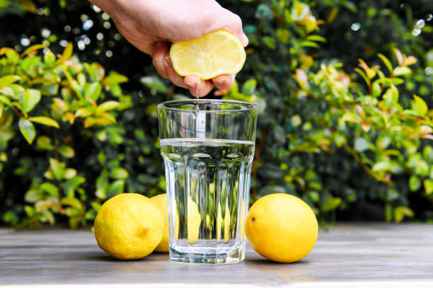 apertando um limão na água. cozinhando água com limão. - lemon juice horizontal composition fruit - fotografias e filmes do acervo