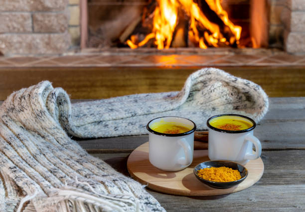 istock Golden latte milk made with turmeric and spices before cozy fireplace. 1221683692