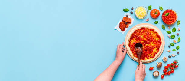 istock Putting pizza sauce on the dough with a wooden spatula 1221683773