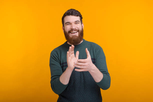 allegro uomo sorridente sta applausando su sfondo giallo. - battere le mani esprimere a gesti foto e immagini stock