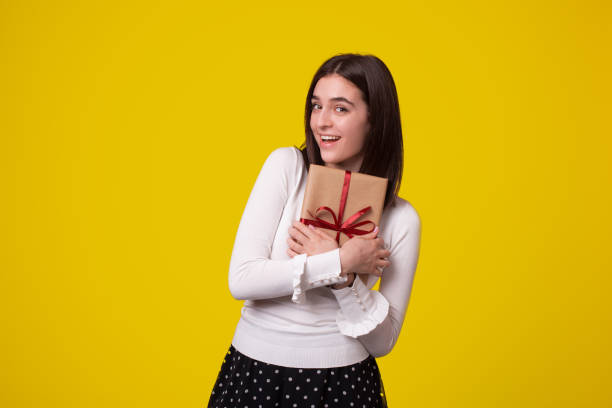 istock Cheerful young woman holding a gift looking at the camera. 1221684027