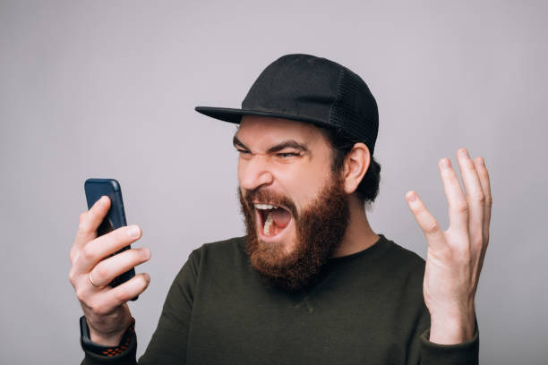 istock Screaming man is looking to his phone on white background. 1221684060
