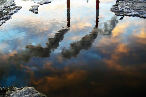 istock Reflection in puddle of three smoked industry chimneys. Air pollution concept. 1221684108