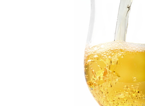 white wine being poured into glass on white background