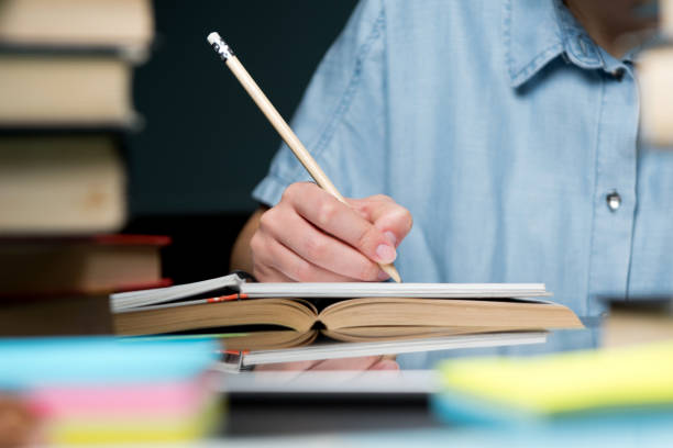 istock Pencil in the hand of a student. She takes notes in a notebook. 1221686487