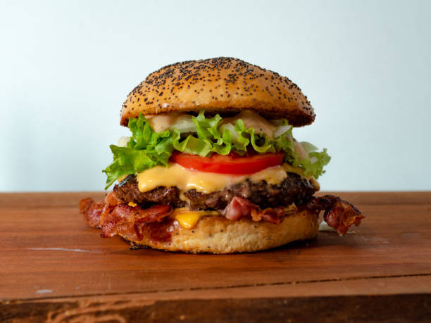 Bacon cheeseburger A big bacon cheeseburger, made with fresh baked buns, bacon, tomato,cheese,onions,salad and a beef patty. bacon cheeseburger stock pictures, royalty-free photos & images