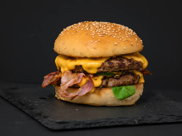 Double cheeseburger Big double cheeseburger, made out of fresh backed buns, 2 beef patty, cheese, salad, tomatoes, bacon and bacon-jam bacon cheeseburger stock pictures, royalty-free photos & images