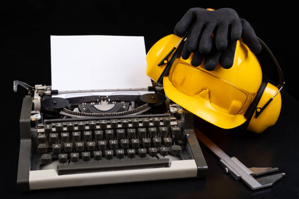 istock A construction helmet on an old typewriter. Measuring instruments used in heavy industry. Dark background 1221689747