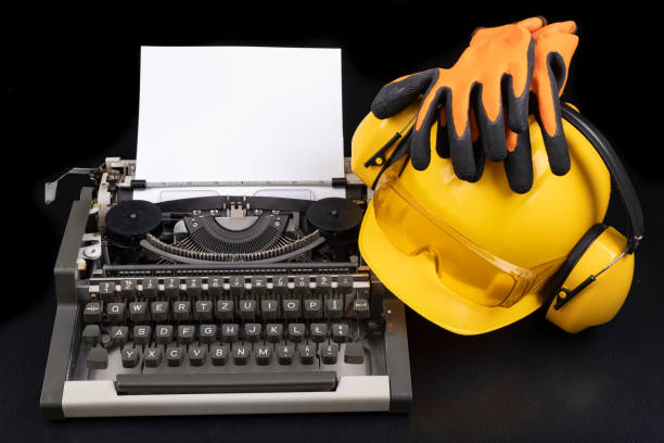 istock A construction helmet on an old typewriter. Accessories for the engineer in the office. Dark background 1221689849