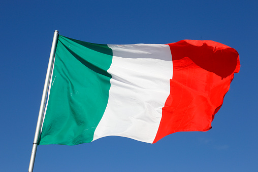 Close-up of the Italian national flag against a blue sky.