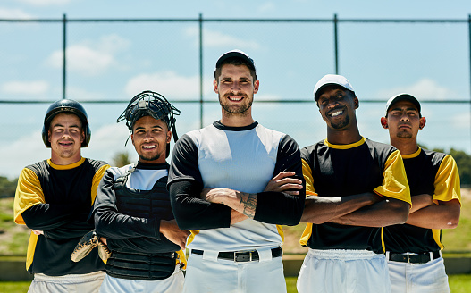 Cropped portrait of a group of baseball players standing with their arms folded on the field during the day