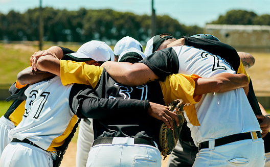 Cropped shot of a team of unrecognizable baseball players standing together in a huddle on the field