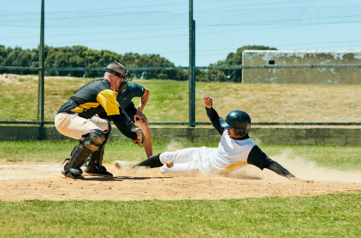 Full length shot of a young baseball player reaching base during a match on the field