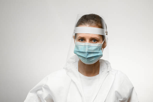 istock young female nurse in medical mask and protective shield on her head 1221692475