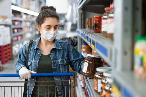 Young woman shopping in a grocery store and wearing protective medical mask stock photo