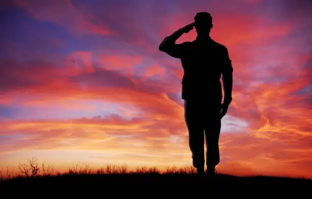 Photo of Soldier full body silhouette saluting gesture at sunset copy space