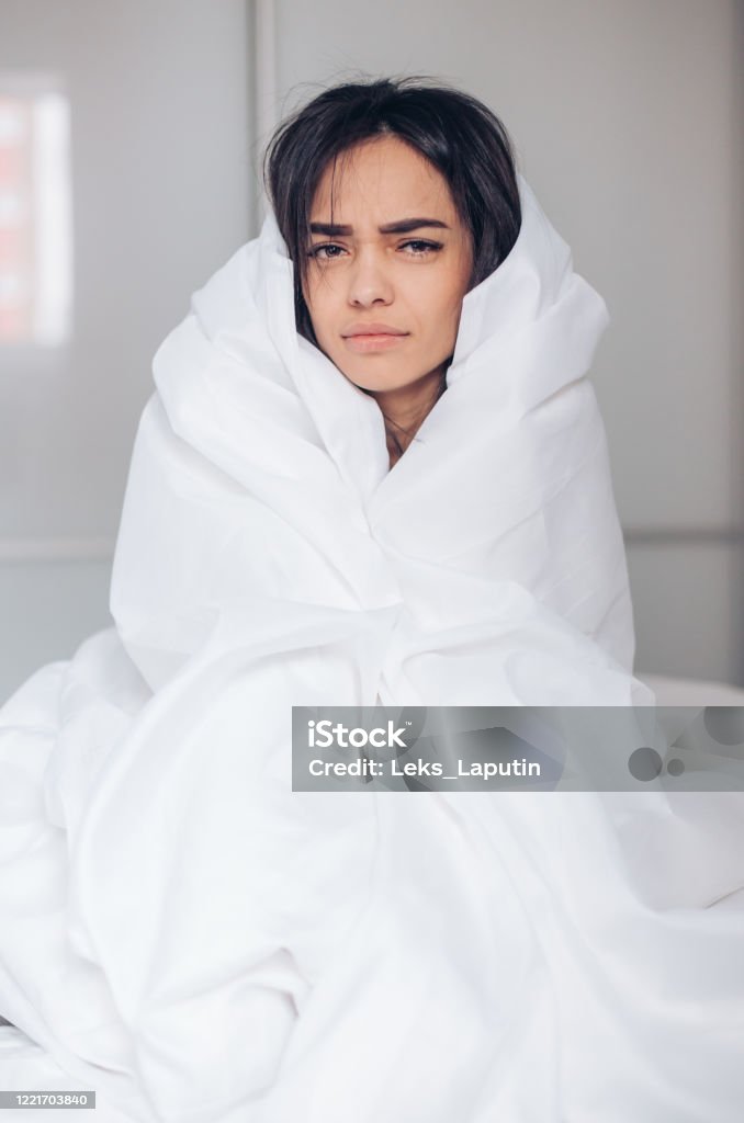 Monday morning. Beautiful young dissatisfied woman wrapped in blanket sitting on bed Monday morning. Beautiful young dissatisfied woman wrapped in blanket sitting on bed at home Blanket Stock Photo