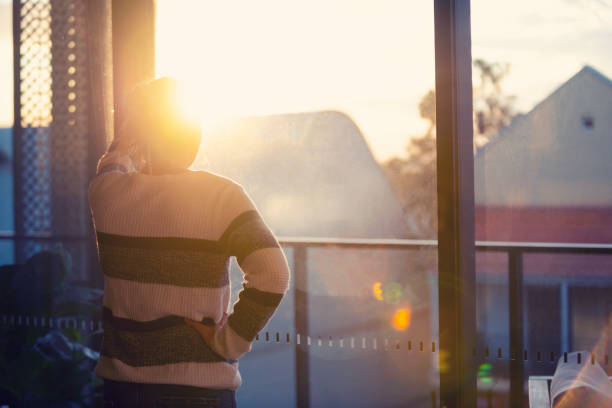 Woman looking through the window at sunset.