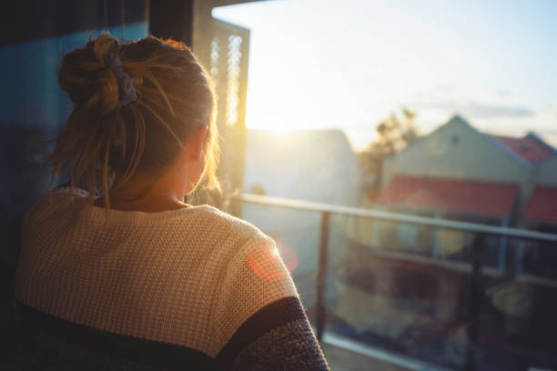 istock Woman looking through the window at sunset. 1221705980