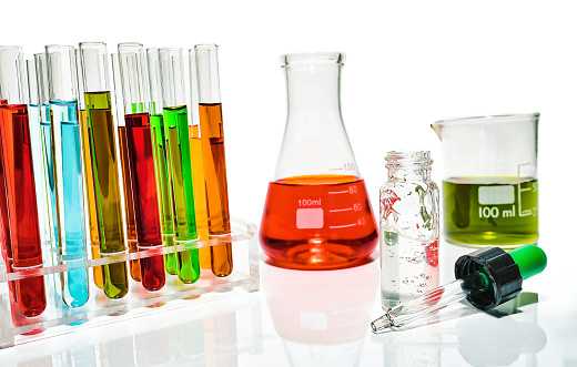 glass in a chemical laboratory filled with liquid of many colors during the reaction.