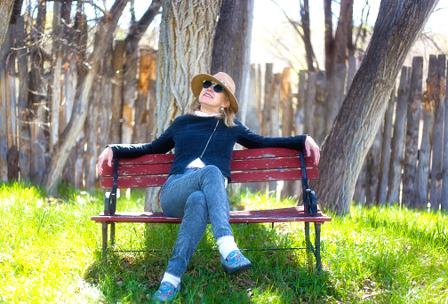 Smiling Woman Relaxing on Red Bench in Springtime